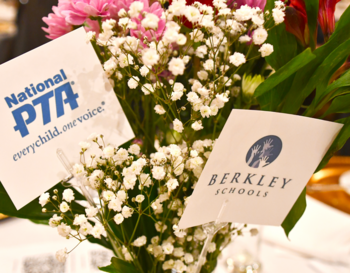 Floral centerpiece featuring signs for National PTA and Berkley Schools, surrounded by pink flowers and white baby's breath.