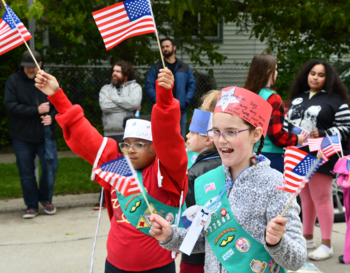 Students enthusiastically wave American flags during a parade.