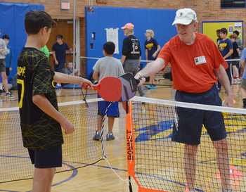 Student getting ready to play pickleball with senior citizen.