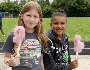 Two young girls smiling holding pink cotton candy