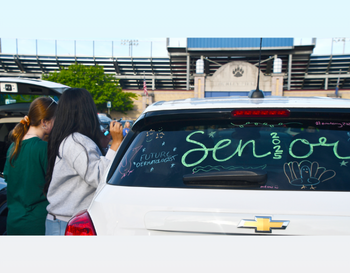 Two individuals decorating a car with the word